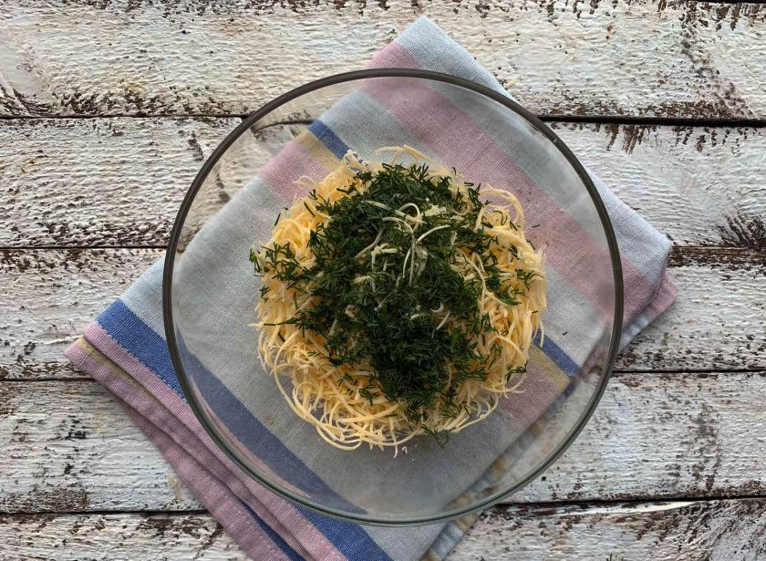 1. Этап. Салат Избушка из крабовых палочек: Зелень мелко порубите и добавьте к сыру.