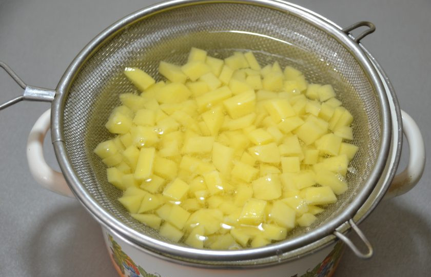 1. Этап. Пицца по-немецки: Нарежьте кубиком картошку и отварите её в ситечке.