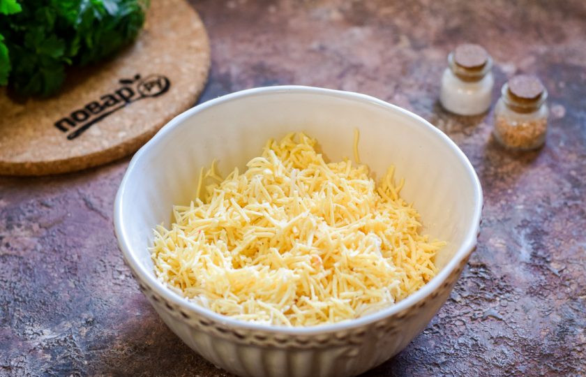 1. Этап. Крабовые палочки Очаровашки: Твердый сыр натрите на мелкой терке и добавьте в миску к плавленому сыру.