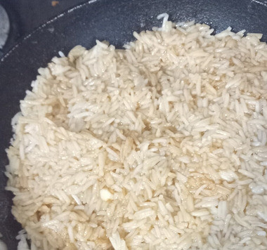 1. Этап. Тайский рисовый салат: На среднем огне разогреть сковороду. Положить туда рис, смешанный с заправкой. Утрамбовать его с помощью обратной стороны ложки. Готовить 10 минут до карамелизации риса.