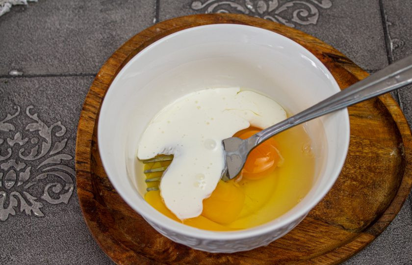 1. Этап. Трёхслойный торт-омлет: Для первого омлета в чашу вбейте 2 куриных яйца, добавьте 1 столовую ложку сливок, соль и перец по вкусу.