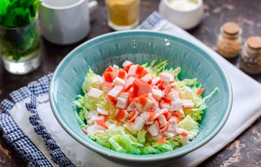 1. Этап. Салат с крабовыми палочками, креветками и ананасами: Крабовые палочки разморозьте и нарежьте небольшими кусочками, добавьте палочки в салатник.