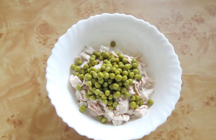 1. Этап. Салат из курицы с рисом: Выложите в салат консервированный зеленый горошек.