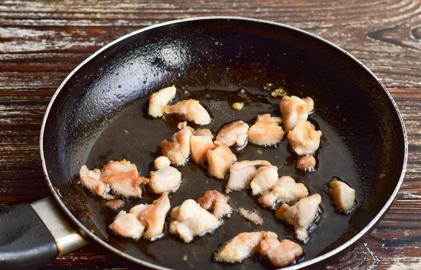 1. Этап. Салат Чебурашка с курицей: В сковороде нагрейте растительное масло, выложите куриное бедро, которое предварительно нарежьте на кусочки (косточку обязательно удалите). Обжарьте мясо на среднем огне в течение 3-5 минут. Посолите его и поперчите.