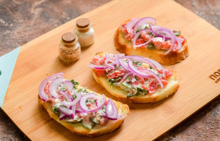 1. Этап. Брускетты с мидиями: Выложите на батон приготовленную массу из помидоров, поверх уложите немного лука.