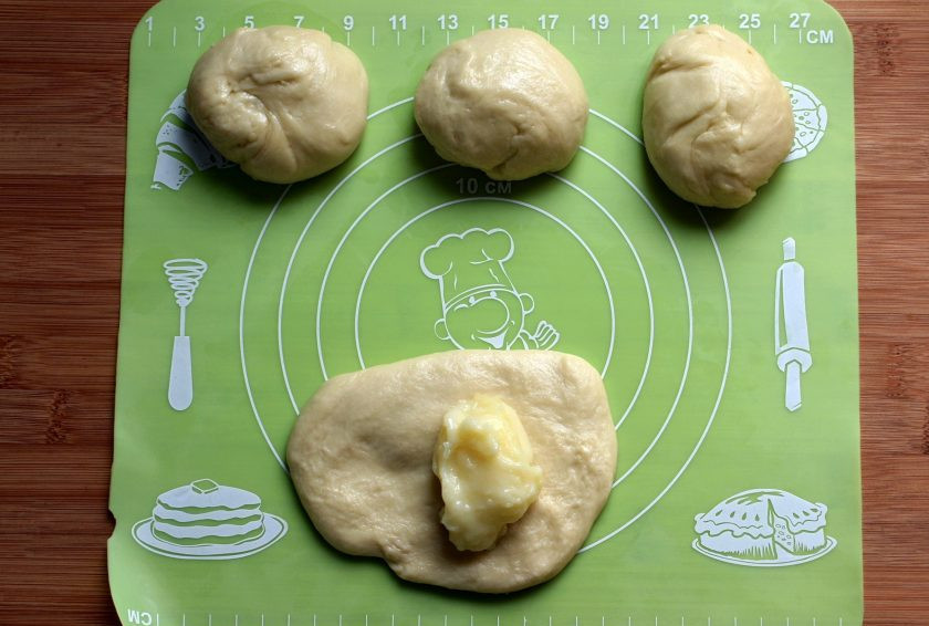 1. Этап. Сайки с заварным кремом: Дайте тесту подойти минимум вдвое и разделите его на кусочки размером с яйцо. Расплющите кусочек теста рукой, тесто нежное и вполне обойдется без скалки. Выложите немного заварного крема ближе к краю лепешки, подверните края и заверните булочку-рулетик.