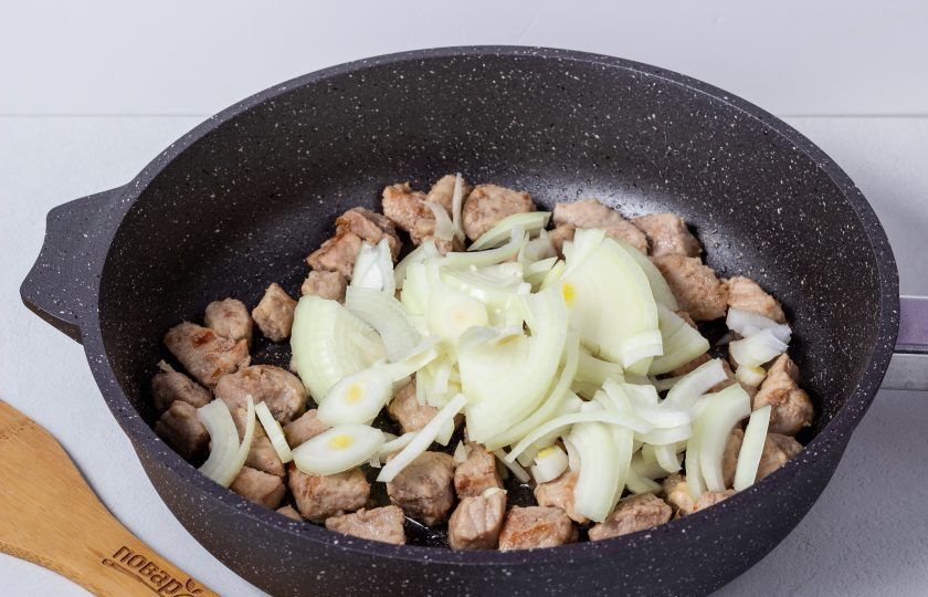 1. Этап. Капуста жареная с мясом на сковороде: Лук нарежьте полукольцами. Обжарьте пару минут с готовым мясом.