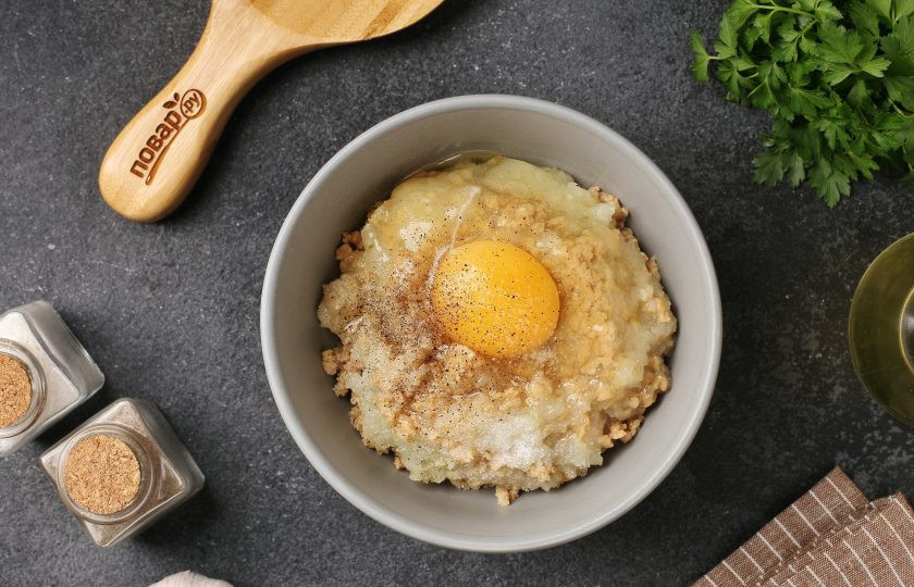 1. Этап. Котлеты из маринованных грибов: Добавьте тёртый на крупной тёрке лук, яйцо, соль и молотый перец по вкусу.