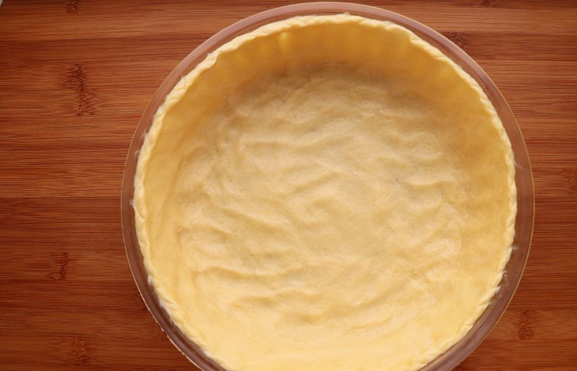 1. Этап. Американский тыквенный пирог: Охлажденное тесто слегка раскатайте и выложите в смазанную маслом форму для выпечки, руками создав бортики. Наколите тесто вилкой и застелив бумагой для выпечки насыпьте сверху фасоль или любые другие бобовые. Выпекайте при температуре 220 градусов 10 минут, затем уберите фасоль и выпекайте еще 5 минут. Вытащите корж из духовки.