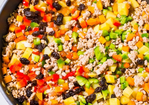 1. Этап. Свинина с изюмом: Далее добавьте морковь и картофель без воды, а также перец и изюм. Влейте томатный и соевый соус. Всыпьте соль и перец.