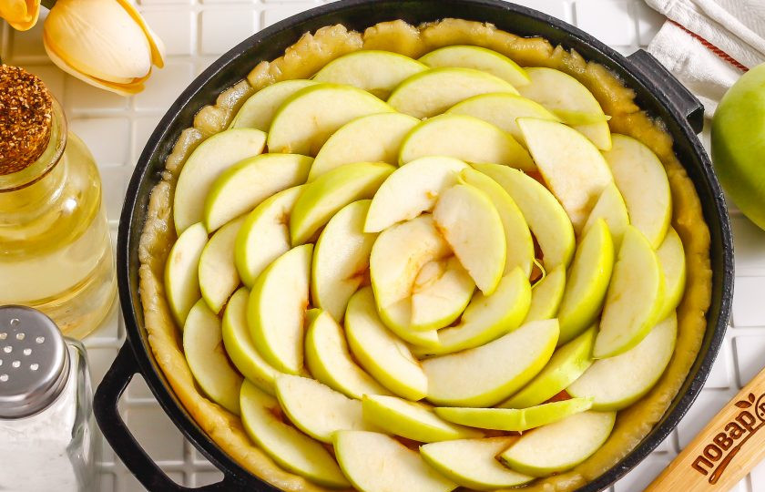 1. Этап. Песочный пирог с вареньем и яблоками: Разрежьте яблоки на четыре части и срежьте семенные блоки. Промойте в воде и нарежьте каждую четвертинку дольками. Выложите нарезку на варенье. Разогрейте духовку до 180 градусов.