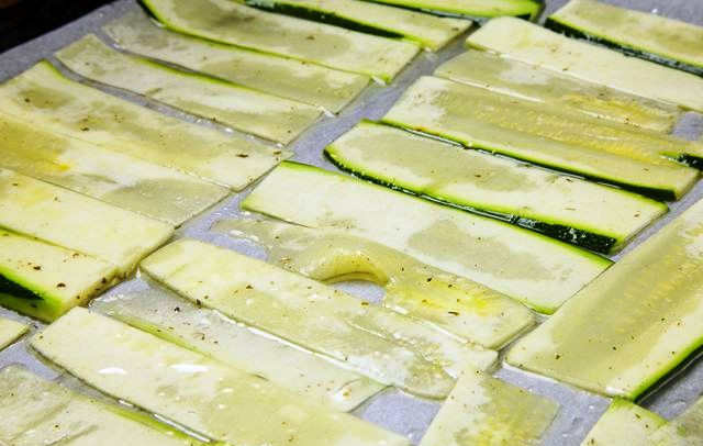 1. Этап. Салат с жареным халуми: Цуккини порежьте тонкими полосками, перемешайте с растительным маслом и разложите на противне. Поставьте в духовку на 10 минут.