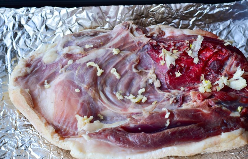 1. Этап. Утка в духовке с чесноком: Выложите половину утки на противень, который застелите фольгой. Выдавите чеснок.