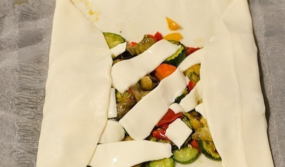 1. Этап. Штрудель с овощами: 2. Раскатайте в пласт слоеное тесто, выложите овощи, сверху разместите ломтики сыра (можно натереть сыр на терке), сверните в рулет, хорошо закрепив все края.