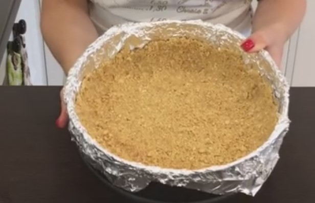 1. Этап. Вкусный домашний чизкейк: 2. Круглую форму для выпечки полностью застелите фольгой. Отправьте туда основу для чизкейка, пальцами распределите таким образом, чтобы получилось дно и бортики. Отправьте в холодильник на час.