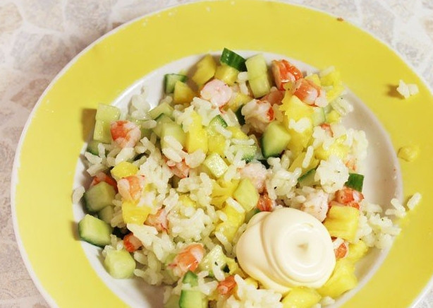 1. Этап. Салат с креветками и рисом: Рис отварите до готовности в подсоленной воде. Воду слейте, а рис переложите в миску. Добавьте к нему огурцы, мякоть ананаса и креветки. Заправьте все майонезом и посолите. Перемешайте содержимое миски, выложите его в половинки ананасов.