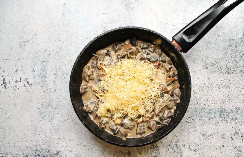 1. Этап. Грибы на сковороде со сметаной и сыром: Сыр натрите на средней терке, перемешайте.