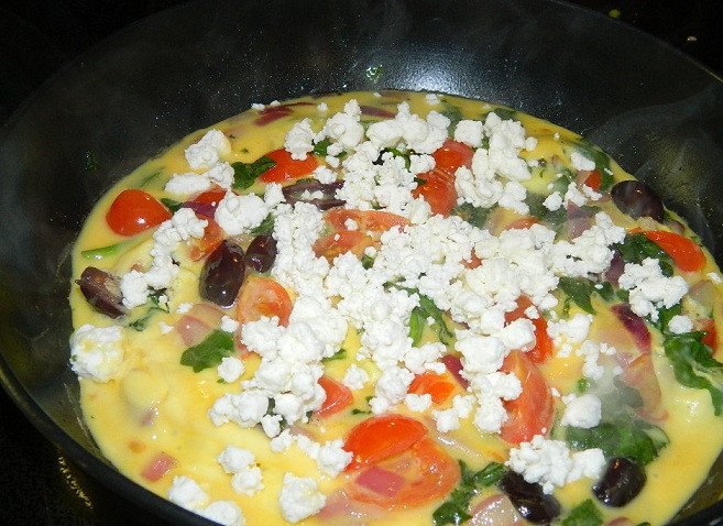 1. Этап. Омлет по-гречески: 7. Когда верхушка омлета немного схватится, выложить на омлет сыр, предварительно раскрошив его.