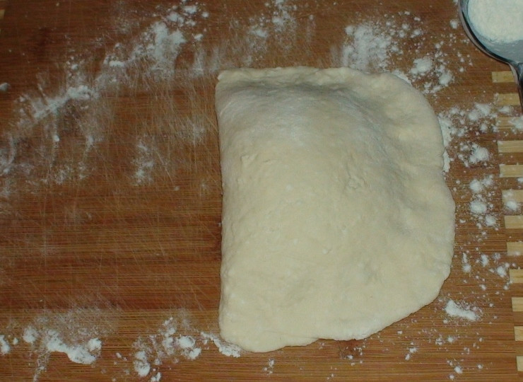 1. Этап. Пирожки на кефире жареные: На посыпанную мукой дощечку выкладываем тесто для формирования одного пирожка. Раскатываем из него полукруг. На одну сторону полукруга кладём начинку, другой стороной закрываем.