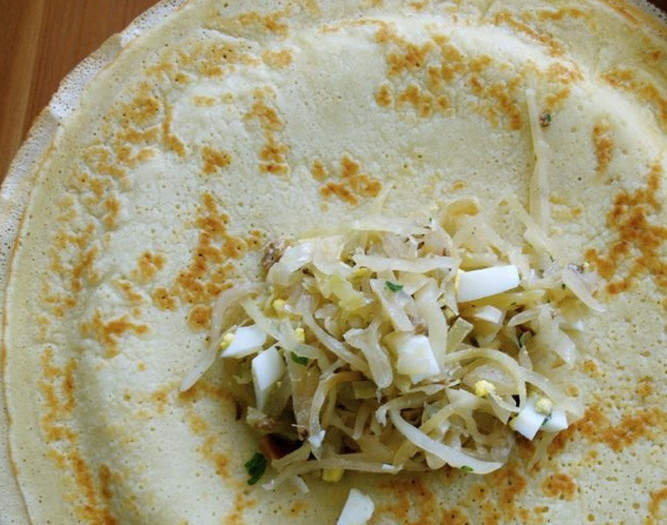 1. Этап. Блины с капустой и яйцом: 8. Возьмите один блинчик, выложите в центр немного начинки и заверните. Начините все блинчики таким же образом.