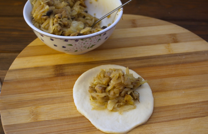 1. Этап. Дрожжевые пирожки с капустой: Раскатайте первый шарик в блинчик. Выложите начинку (1 ст. ложку). Сформируйте пирожок.