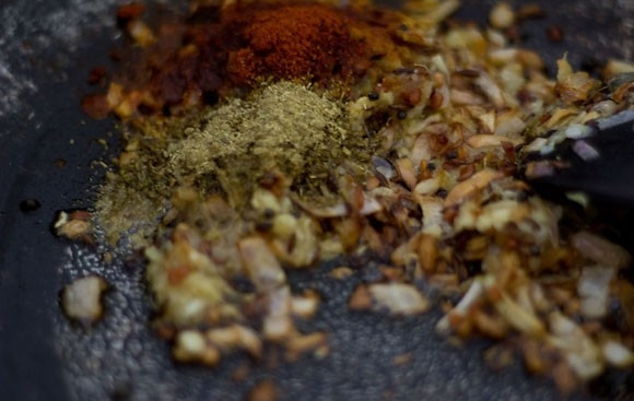 1. Этап. Карри с рисом, горошком и грибами: Когда лук обжарится, добавьте специи и измельченные кешью. Обжаривайте несколько минут.