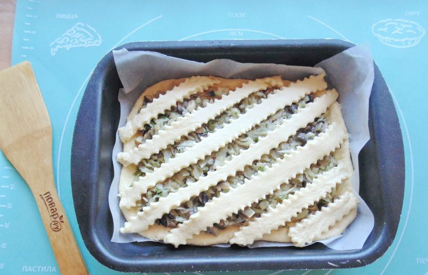 1. Этап. Пирог с капустой и грибами: Вторую часть теста раскатайте и нарежьте полосками. Выложите полоски на начинку.