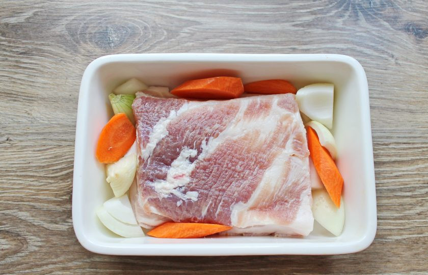 1. Этап. Свинина по-датски: Овощи почистите и порежьте крупными кусками. Выложите их на дно формы для выпечки. Уложите на них свинину кожей вниз.