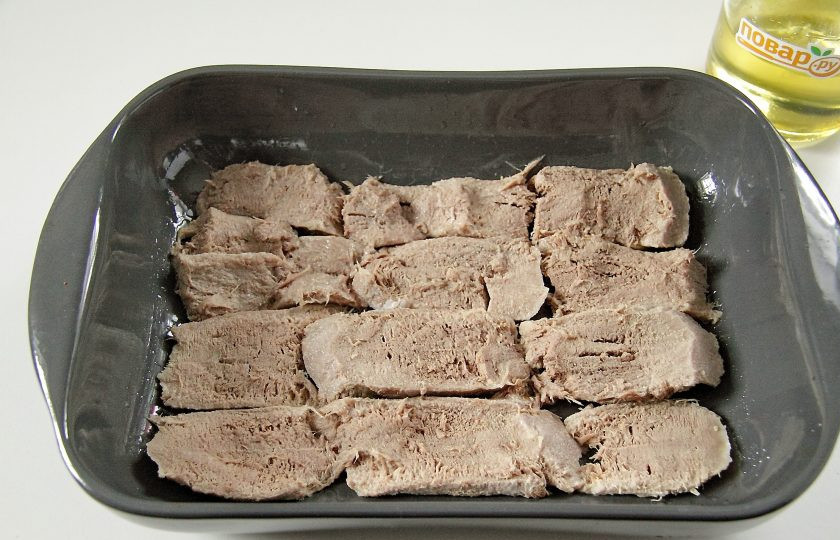 1. Этап. Язык под шубой: Форму для запекания смажьте маслом. Язык очистите, нарежьте пластинами, толщиной не более 1 см, и выложите в один ряд.