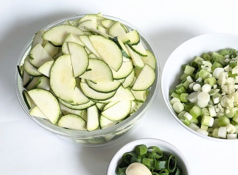 1. Этап. Быстрая сковорода с цукини и лососем: Цукини нарезать тонкими полукольцами, белую часть лука и 2 дольки чеснока отдельно. Зелёную часть нарезать отдельно отставить в сторону вместе с одной долькой чеснока.