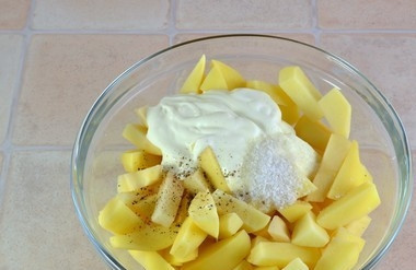 1. Этап. Картофель с курицей в духовке: Добавьте к картофелю соль, перец и половину сметаны. Всё перемешайте.