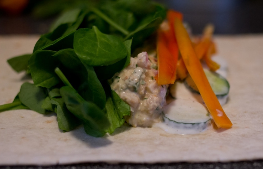 1. Этап. Лаваш без сыра: Разложите лаваш, выложите по центру немного начинки из нута. Добавьте огуречную заправку, а также несколько ломтиков красного сладкого перца и пару листиков шпината. Заверните, как шаурму.