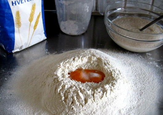 1. Этап. Тесто на пончики: Сначала разводим в теплом молоке дрожжи. Кладем сахар, размешиваем и отставляем бродить. А пока просеиваем муку. Делаем углубление в центре горки. Разбиваем туда яйца. Наливаем дрожжи с молоком, кладем щепотку соли и замешиваем тесто.