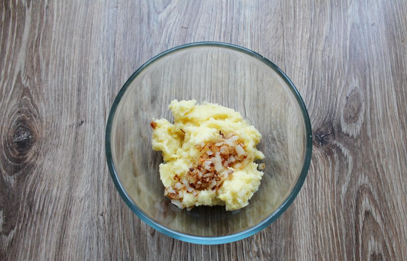 1. Этап. Форель под шубой в духовке: Выложите в картофель обжаренный лук.