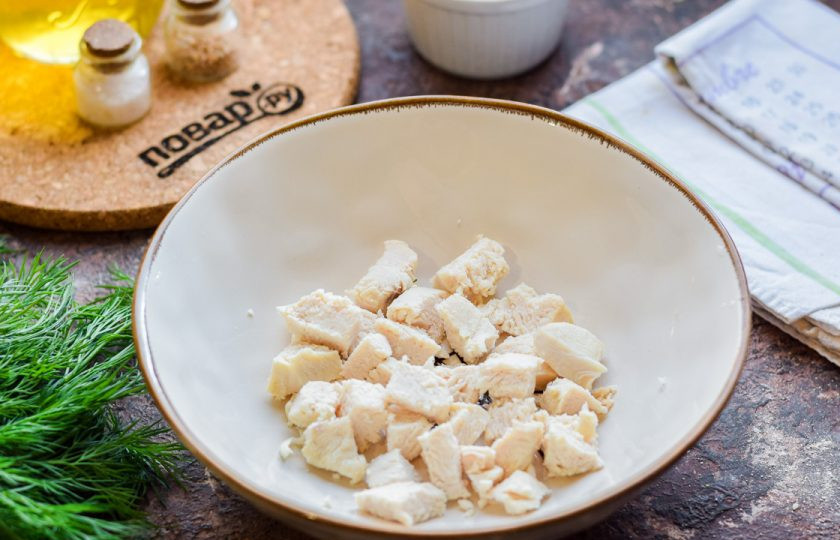 1. Этап. Салат Кокетка с курицей: Куриное филе отварите заранее в подсоленной воде, остудите в бульоне. Нарежьте филе небольшими кубиками и переложите в салат.