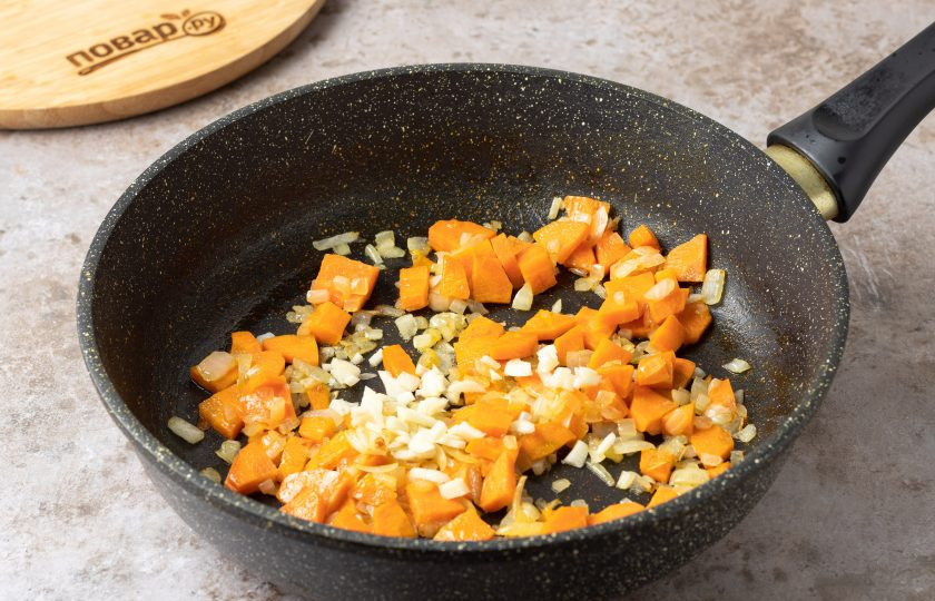 1. Этап. Крем-суп из красной чечевицы: Разогрейте сковороду на среднем огне и обжарьте нарезанный кубиками репчатый лук около 2 минут до прозрачности. Добавьте морковь нарезанную ломтиками среднего размера и готовьте еще 3-4 минуты. После добавьте мелко порубленный чеснок и жарьте все вместе 1 минуту.