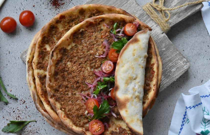 1. Этап. Лахмаджун по-турецки: На центр лепешки выложите маринованный лук с зеленью и сумахом. Для сочности можно добавить кусочки помидоров. Дополнительно подайте дольки лимона или лайма.