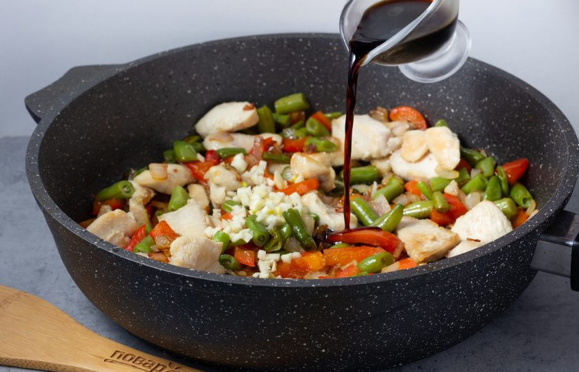 1. Этап. Теплый салат со стручковой фасолью и курицей: В последнюю очередь в сковороду добавьте рубленный чеснок, готовое куриное филе и соевый соус.