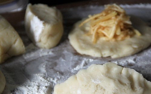 1. Этап. Пирожки с яблоком: Тесто скатайте в жгутики и разрежьте на равные части. Каждую из них раскатайте в лепешку на присыпанной мукой рабочей поверхности. Выложите в центр лепешек начинку из яблок. Защипните края теста, сформировав пирожки.