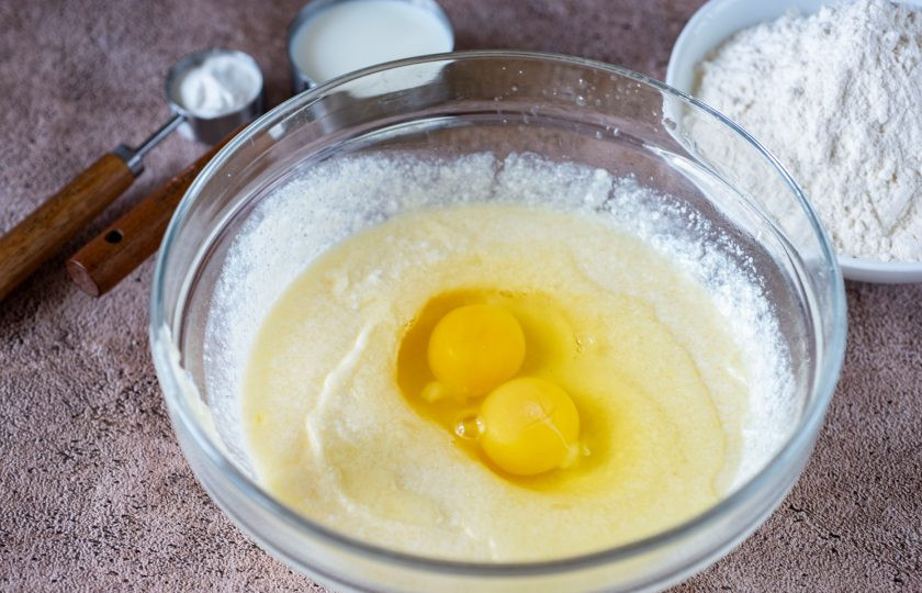 1. Этап. Творожные пончики в мультипекаре: К творожной смеси вбейте яйца. Венчиком активно все перемешайте.