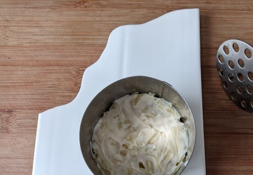 1. Этап. Салат Тунец в тулупе: Кладём картофель первым слоем, слегка приминаем толкушкой, солим по вкусу, смазываем майонезом.