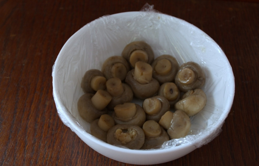 1. Этап. Салат Грибная полянка с курицей: На дно миски шляпками вниз выкладываем шампиньоны целыми.