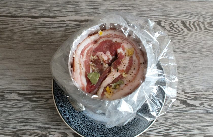 1. Этап. Грудинка в ветчиннице: Возьмите ветчинницу, вложите в нее обычный пакет, а в него пакет для запекания. После положите подготовленную грудинку. Края пакетов заправьте внутрь.