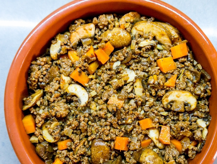 1. Этап. Английский пастуший пирог: Форму для запекания смажьте маслом и всыпьте начинку из фарша и грибов.