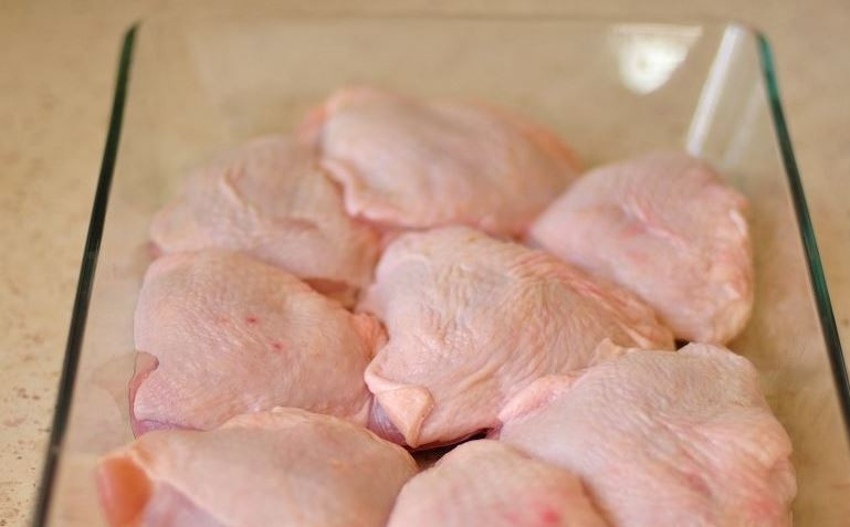 1. Этап. Рецепт курицы с апельсинами в духовке: Куриные бедрышки вымойте, обсушите бумажными полотенцами. Обрежьте лишний жир и удалите остатки перьев. Возьмите жаропрочную посуду и выложите в нее курицу.