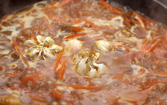 1. Этап. Плов на сковороде: Вливаем в сковороду 500 миллилитров воды и кладем в середину две головки чеснока. Когда жидкость закипит, чеснок можно достать и отложить в сторону. Теперь солим воду.