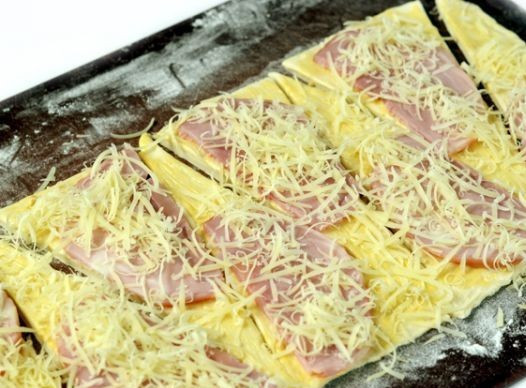 1. Этап. Круассаны с сыром и ветчиной: Мелко натираем сыр и распределяем его поверх ветчины.