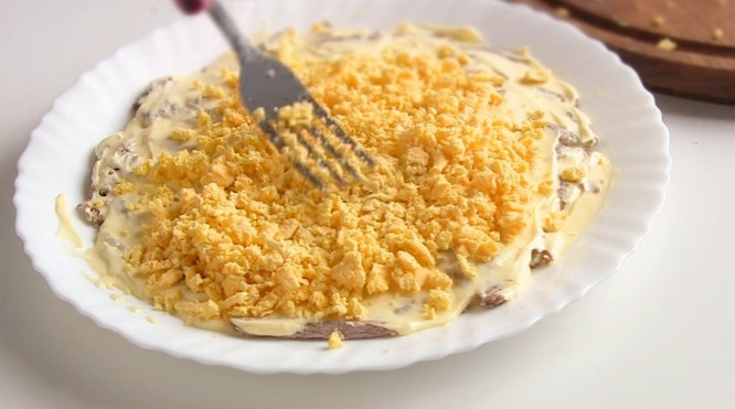 1. Этап. Простой слоеный салат Сказка: 2. Яйца сварите вкрутую. Отделите желтки от белков. Натрите желток на терке и положите вторым слоем в салат.