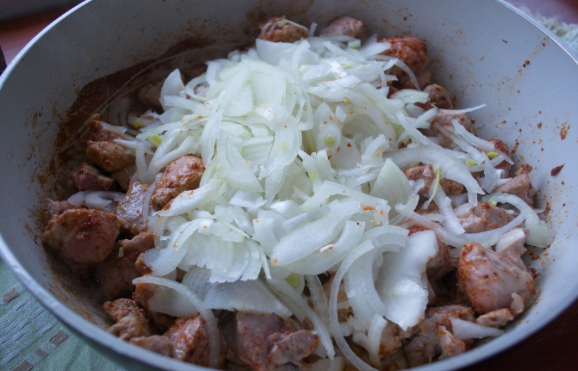 1. Этап. Гуляш из свиного окорока: К обжаренному мясу добавьте репчатый лук. Пассеруйте все вместе до мягкости лука.