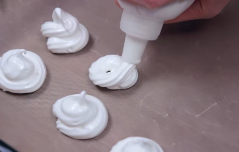 1. Этап. Малышки-безе: 3. Масса должна получиться очень густой и хорошо держать форму. Переложите ее в кондитерский мешок и на застеленный пергаментной бумагой противень высадите небольшие безе, оставляя немного расстояния между ними.